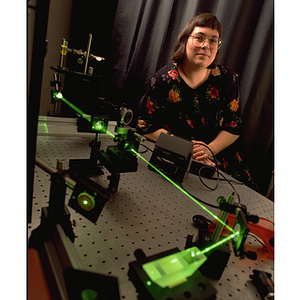 A young woman poses with laser equipment she uses during her engineering co-op