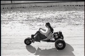 Young woman riding motorized trike on beach
