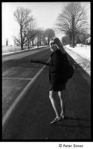 Karen Helberg walking down a snowy road with her acoustic guitar, looking back to the camera