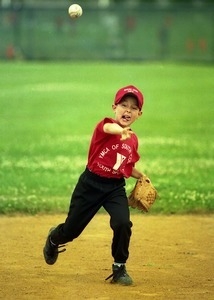 Young boy throwing a baseball in a YMCA South County youth game