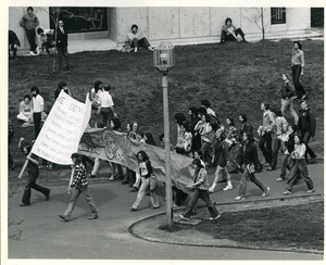 Board of Trustees fee increase demonstration: protestors holding banner and sign, marching from the Student Union to the Whitmore Administration Building