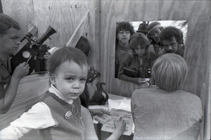 May Day concert and demonstrations: journalists waiting for press passes, child in foreground, Danny Schechter in background