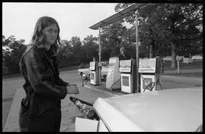 Young woman in overalls, pumping gas at an Exxon service station