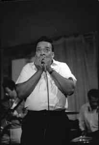 James Cotton at Club 47: James Cotton playing harmonica into a microphone onstage as he looks upward, with Luther Tucker playing guitar at left, and Francis Clay playing drums at right