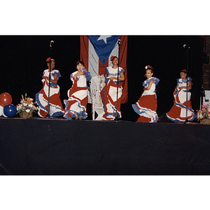 Five girls dance on stage in Puerto Rican flag dresses at the Festival Puertorriqueño
