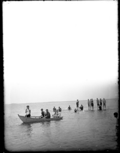 People in a boat and standing in the water at low tide