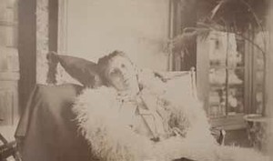 Emily Beale in hammock in glass room, wrapped in white fur