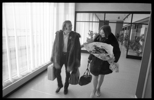 Stephen Stills (in heavy fur coat) and Judy Collins (with a bouquet of roses) walking through an airport