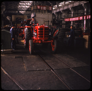 Tractor factory with workers inspecting a new machine