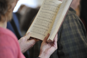 Aftermath of the Congregational Church fire in West Cummington, Mass.: close-up of parishioner singing from a hymnal