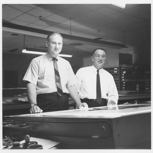 Edwin Rossman and unidentified man standing at large light table