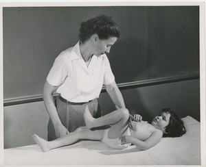 Betty Ann Feinstein examining a young girl with cerebral palsy