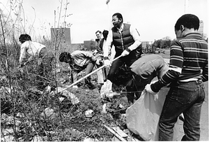 Mayor Raymond L. Flynn cleaning debris from a lot with six unidentified people