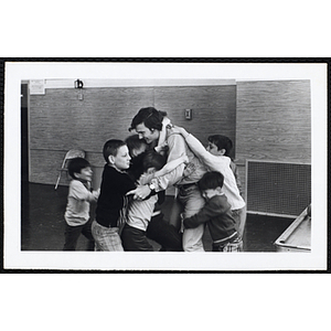 Six boys trying to hug a man at once during a Boys' Club event