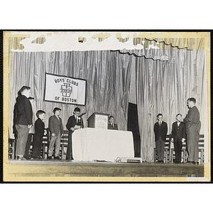 An unidentified man addresses a group of boys on stage at a Boys' Clubs inagural and ball event