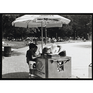 A teenage boy serves ice juice from a food cart to two boys on Boston Common