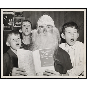 Three singing boys pose with Santa Claus who holds a "Three-Part Choruses for Male Voices" booklet