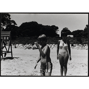 A boy and a woman stand on a beach