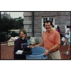 A woman and a man hold a garbage can during the Battle of Bunker Hill Road Race