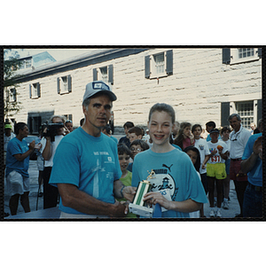 A man and a girl pose with a trophy as they shake hands during the Battle of Bunker Hill Road Race
