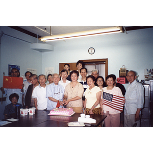 Chinese Progressive Association members gather around a man and women who are cutting cake