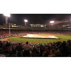 Employees take the rain tarp off the field at Fenway Park