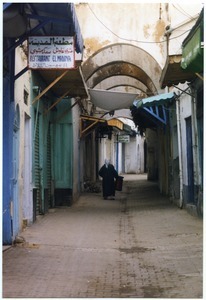 Woman walking through canopied market in ancient Medina, Tunis