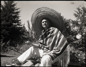 Richard Hallet, seated on rocks, wearing sarape and sombrero