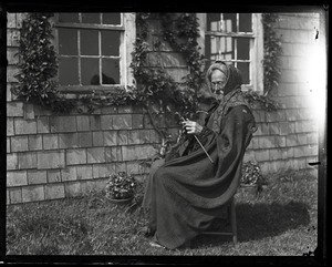 Reuben Austin Snow, the cross-dressing hermit of Cape Cod, seated in front of cottage, knitting