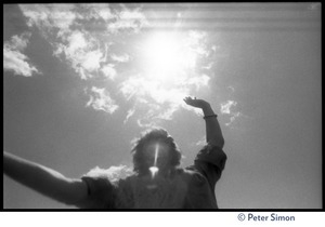Bhagavan Das dancing with arms raised at Sonoma State University, silhouetted against the sun