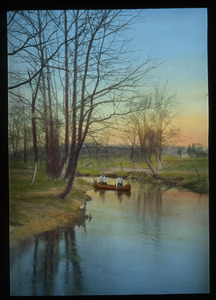 Two people canoeing on a brook alongside a road and fields