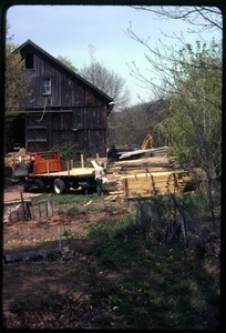 Lumber being stacked in front of the barn, Montague Farm Commune