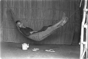 Farmer in hammock taking a midday siesta because he was unable to sleep at night during a Vietcong attack; Luong Hoa Village.