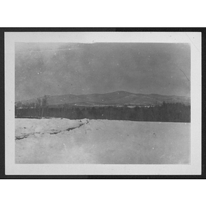 View of snowy field, trees and distant mountain at unidentified YMCA camp