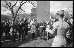 American Nazi Party counter-protester Douglas L. Niles (back to camera), in uniform, carrying a sign, and facing news media: Washington Vietnam March for Peace