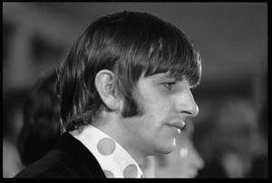 Ringo Starr seated at a table during a Beatles press conference: close-up in profile