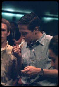 Artist Robert Rauschenberg, lighting a cigarette, at a reception