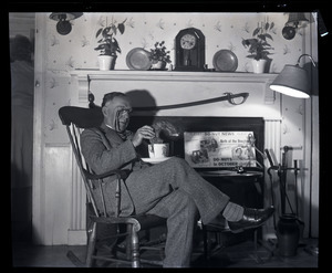 Henry A. Ellis and the doughnut: Ellis seated in front of a fireplace, dunking an oversized donut into oversized cup of coffee