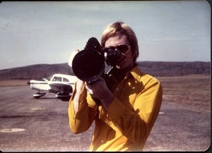 James Baker with video camera, airplane in background