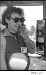 Charles Light (wearing press pass for Green Mountain Post Films) using a pay phone