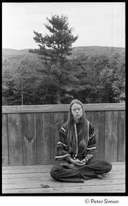 Woman seated in a lotus pose on a deck, meditating, Rowe Center spiritual retreat