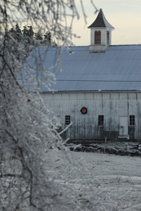 Barn hung with a Christmas wreath and ice-covered landscape