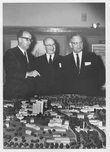 Dean Edward C. Moore with two unidentified men standing above a scale model of the Umass campus