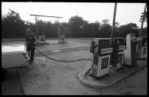 Young woman in overalls, pumping gas at an Exxon service station
