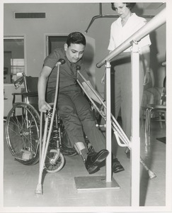 Luis Damilano standing up out of his wheelchair using crutches