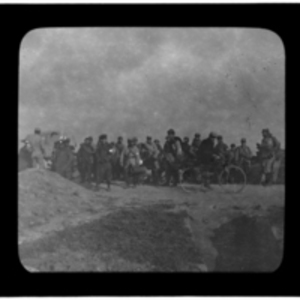 Large group stand in field, with bicyclist