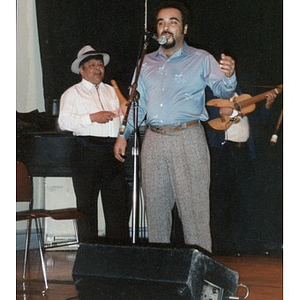 Man singing on stage accompanied by musicians playing traditional Puerto Rican instruments in a Café Teatro performance.