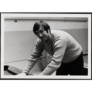 A male staff member leaning over a billiards table and looking at the camera