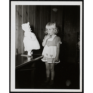 A girl looks at a doll on display at a Boys' Club Little Sister Contest