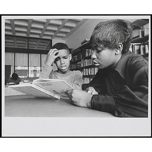 Two boys read "Who Cares!" at a table in a library